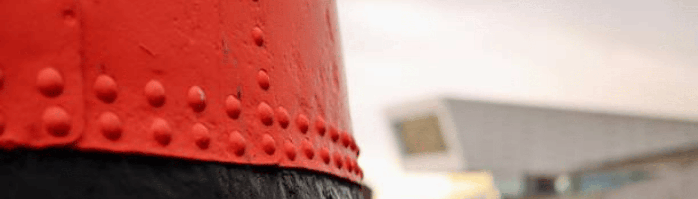 A Detailed Close-up of a Red and Black Riveted Metal Structure at Historic Docks