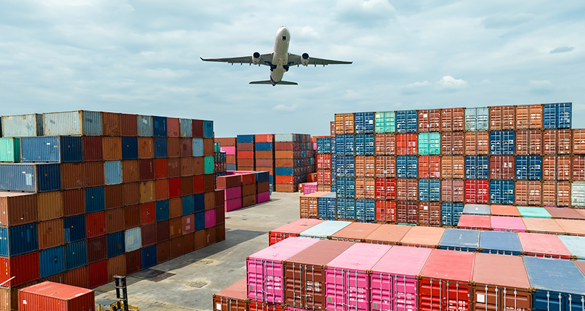 Cargo plane flying over shipping containers representing the transportation industry
