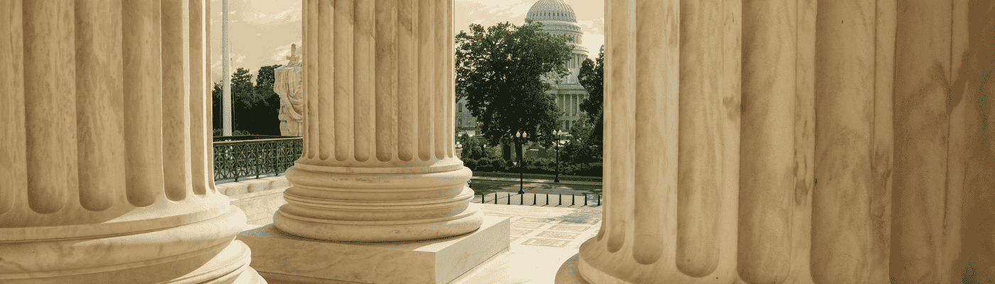 United States Capitol Building viewed between columns of the Supreme Court at sunset